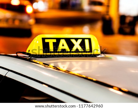 Night picture of a taxi car. Taxi sign on the car roof glowing in the dark