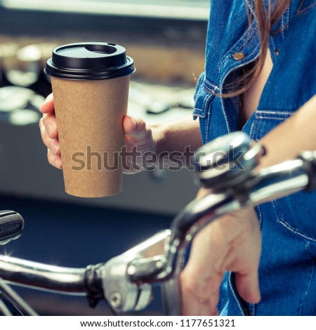 Young woman with disposable coffee cup and bike. Youth, modern lifestyle. Streets of Amsterdam. 
