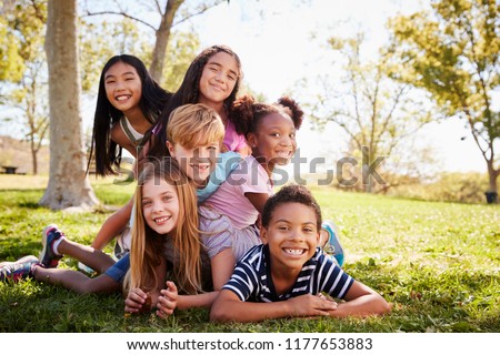 Multi-ethnic group of kids lying on each other in a park Royalty-Free Stock Photo #1177653883