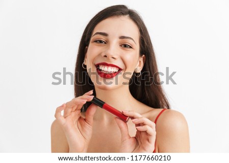 Photo of young happy excited woman posing isolated holding lip gloss doing makeup.