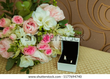 Wedding ring in white gold. Two platinum rings of the bride and groom in a white box and a bouquet of pink roses and white flowers