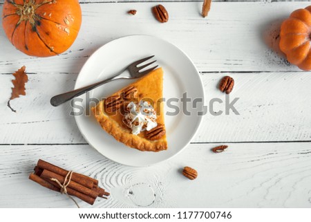 Pumpkin Pie with whipped cream, pecan nut and cinnamon on white wooden background, top view, copy space. Homemade autumn pastry for Thanksgiving - piece of pumpkin pie.