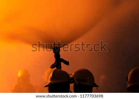 Close-up Fireman training Spray water curtain ,The Back side view of a group of firefighters helped stop the fire. Fire in the Industrial Factory . Rescue ,Education ,Emergency and Teamwork concept .