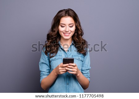 Content trendy cheerful nice cute adorable lovely attractive brunette girl with wavy hair in casual denim shirt, typing in phone, isolated over grey background Royalty-Free Stock Photo #1177705498