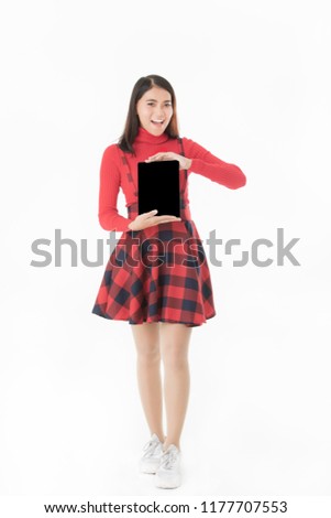 Portrait​ of.peautiful Asain​ woman in red casual dress standing smiling holding tablet in hand blank space isolated on white background.