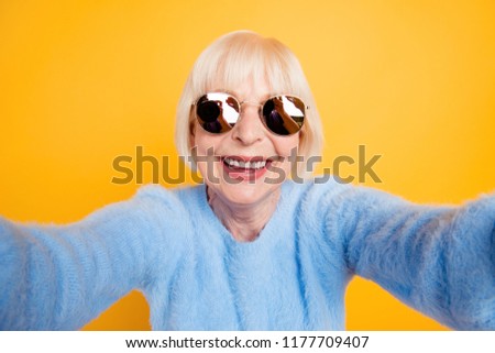Close up portrait of happy grandma taking a selfie on vacation of two hands, isolated on yellow background
