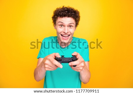 Young attractive handsome cheerful guy wearing casual green polo t-shirt enjoying playing video game. Isolated over vivid shine bright yellow background