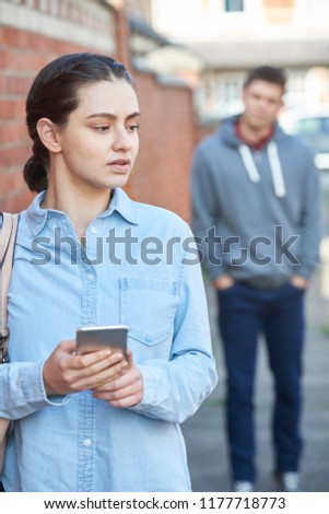 Young Woman Texting For Help On Mobile Phone Whilst Being Stalked On City Street Royalty-Free Stock Photo #1177718773