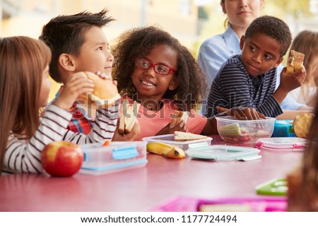 Young school kids eating lunch talking at a table together Royalty-Free Stock Photo #1177724494