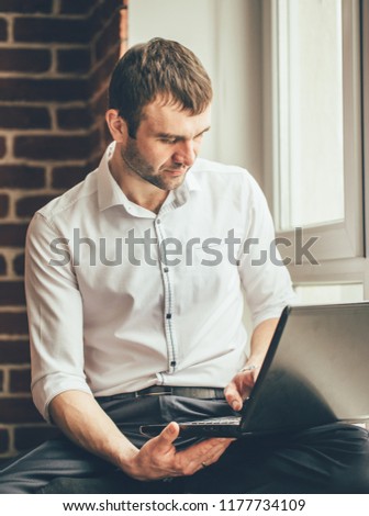 businessman reads business correspondence on his laptop near the window in the office