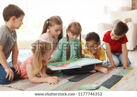 Cute little children reading book together indoors. Learning by playing