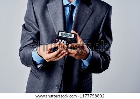 coin and calculator in the hand of a jacket blue shirt tie                               