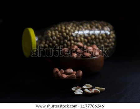 Peanut on Cup made of wood and spoon on black background
