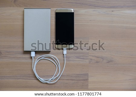 Charging power to phone with powerbank on wood background.