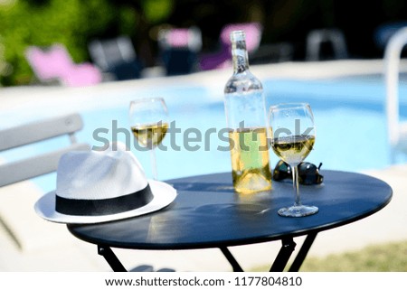two glass of cool white wine with bottle outdoor in a restaurant pool side terrace in sunny summer day