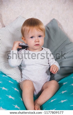 Happy child baby toddler sitting smiling kissing mobile cellphone on a white background