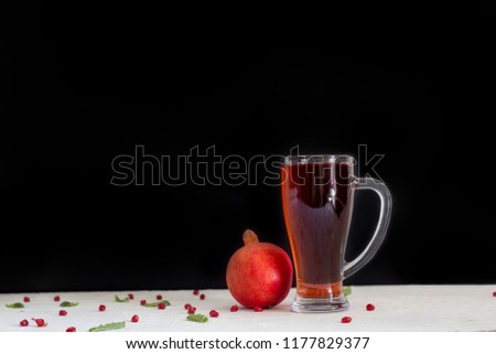 Red Pomegranate and big glass of pomegranate juice with black background