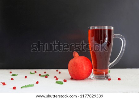 Red Pomegranate and glass of pomegranate juice on wooden board with black background