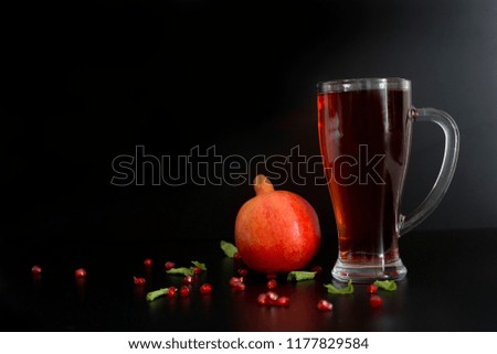 Fresh pomegranate and big glass of pomegranate juice on black background