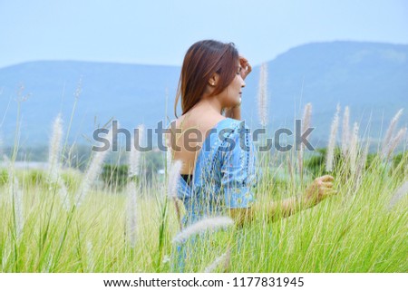 The back of an Asian girl is cheerful in the meadow.