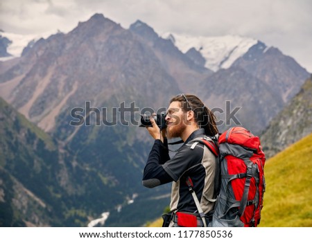 Man photographer with big backpack and camera taking photo of the mountains. Travel Lifestyle concept adventure active vacations outdoor