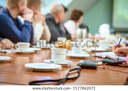 Affiliate business meeting people at the table. Focus on a plate with a cup