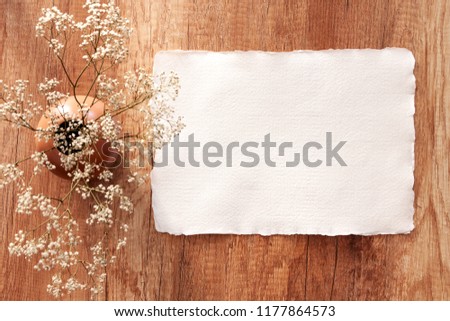 Handmade paper mockup on a wooden table with white field flowers in a vase