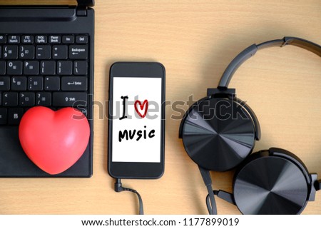 Top view of work space laptop, red heart, smartphone and headphone on wood table with word "i love music".Image concept working and relaxing.