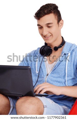 Close up of young man sitting in red pouf using laptop with backpack. Education concept