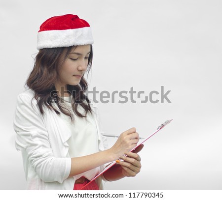 Girl in Santa hat writing. Cute funny photo closeup of christmas woman with copyspace. Isolated on white background.