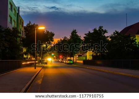 Night shot of a side street with lit lanterns, traffic lights and star-shaped halos