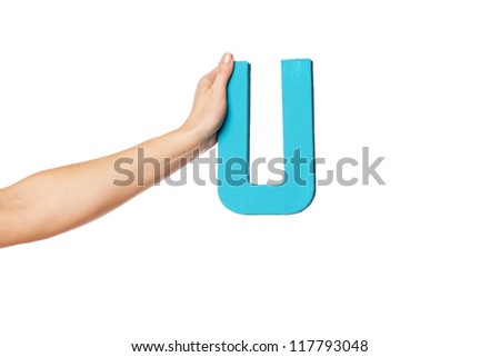 Female hand holding up the uppercase capital letter U isolated against a white background conceptual of the alphabet, writing, literature and typeface