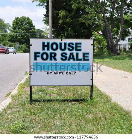 For Sale Real Estate Sign on Suburban Residential Neighborhood Curbside Grass Sunny Day