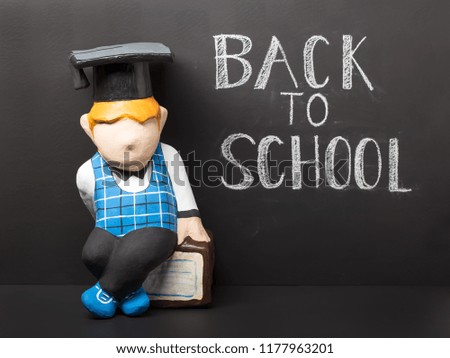 Back to school concept. Cute dummy with book on black chalkboard