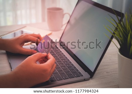 Women hand shopping online with credit card on laptop and smartphone and working wooden desk business with coffee, a little tree.