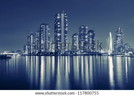 split toned image of Tokyo skyline in modern Tsukishima district with scenic water reflection in Sumida river