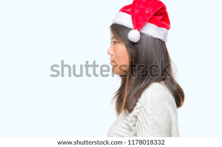 Young asian woman wearing christmas hat over isolated background looking to side, relax profile pose with natural face with confident smile.