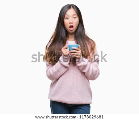 Young asian woman drinking coffee over isolated background scared in shock with a surprise face, afraid and excited with fear expression