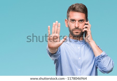 Young handsome man speaking on the phone over isolated background with open hand doing stop sign with serious and confident expression, defense gesture