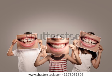 three children holding a picture of a mouth smiling