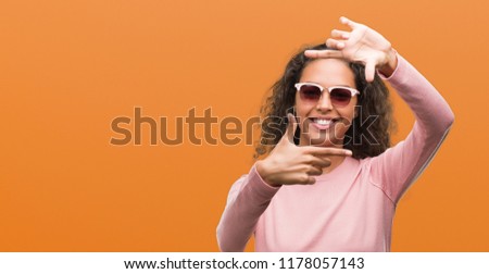 Beautiful young hispanic woman wearing sunglasses smiling making frame with hands and fingers with happy face. Creativity and photography concept.
