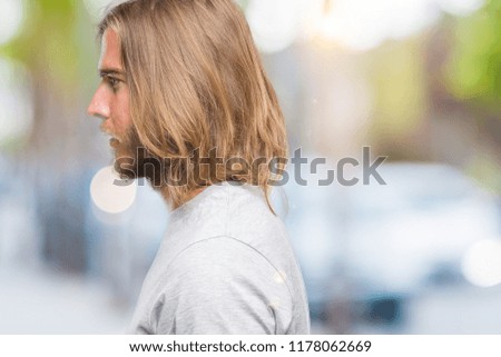 Young handsome man with long hair over isolated background looking to side, relax profile pose with natural face with confident smile.