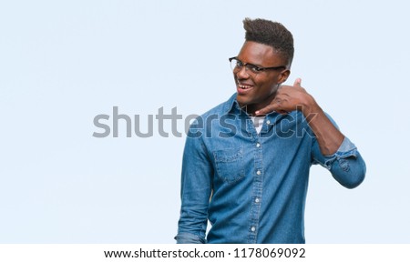 Young african american man over isolated background smiling doing phone gesture with hand and fingers like talking on the telephone. Communicating concepts.