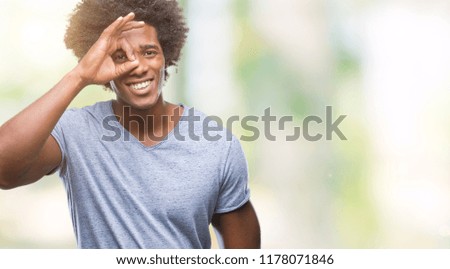 Afro american man over isolated background doing ok gesture with hand smiling, eye looking through fingers with happy face.