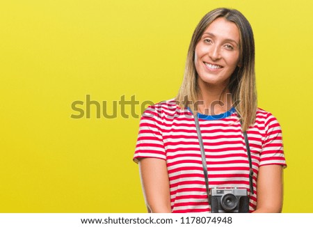 Young beautiful woman taking pictures using vintage photo camera over isolated background happy face smiling with crossed arms looking at the camera. Positive person.
