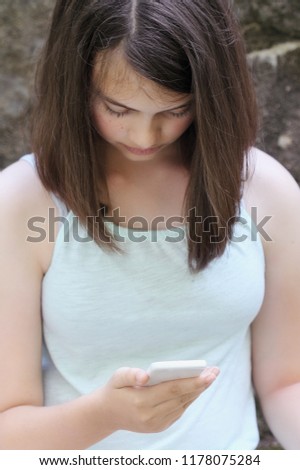 Young teenage girl reading a text message on a smartphone. Selective focus on teen's hand holding phone. 