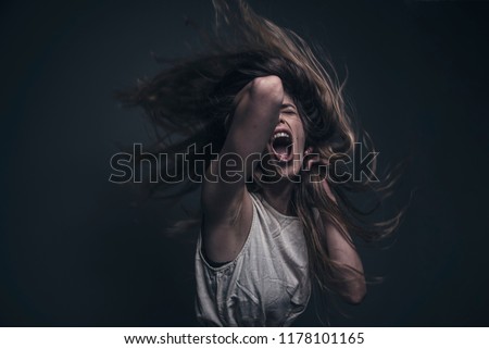 Crazy, deranged young woman screaming with frustration, expressing madness and rage Royalty-Free Stock Photo #1178101165