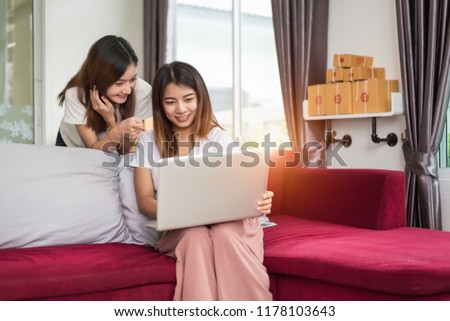 Two young freelancer Asian girl businesswomen private working at home office with laptop computer sitting on sofa. Packaging delivery online shopping service and marketing advertising to customer