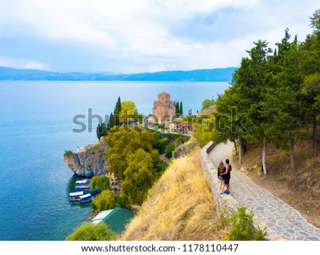 Couple standing on the guardrail looking at the sea and the St. John the Theologian