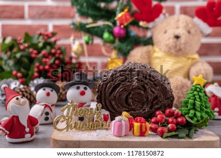 set of Christmas celebration gifts, cake, sugar santa , sugar, snowman, bear doll with background of Christmas tree in front of brick wall